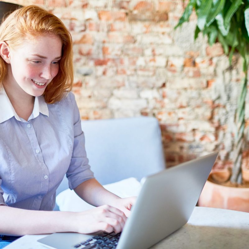 Happy young specialist looking through online vacancies in cafe